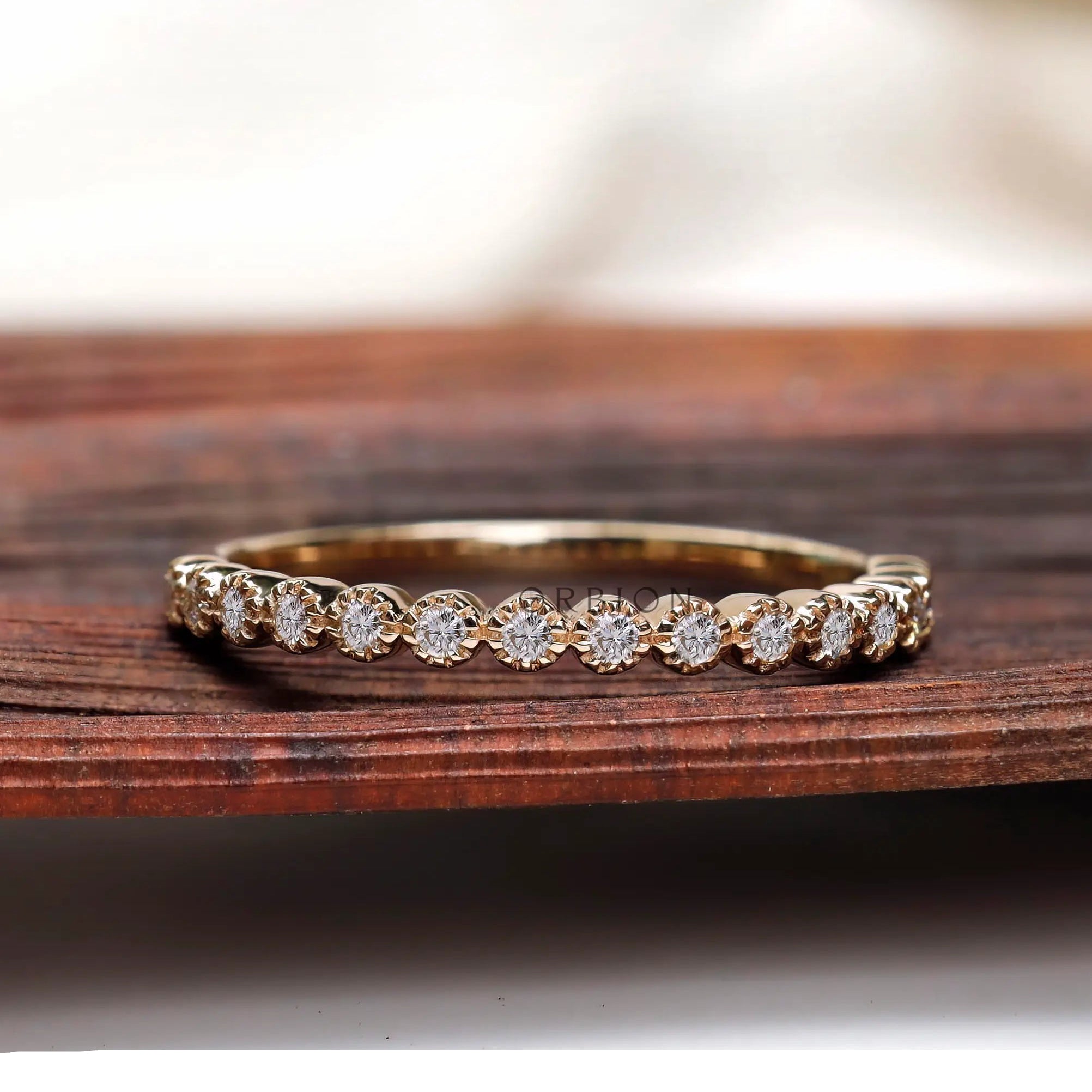 Half eternity bezel set moissanite band displayed on wooden surface front view