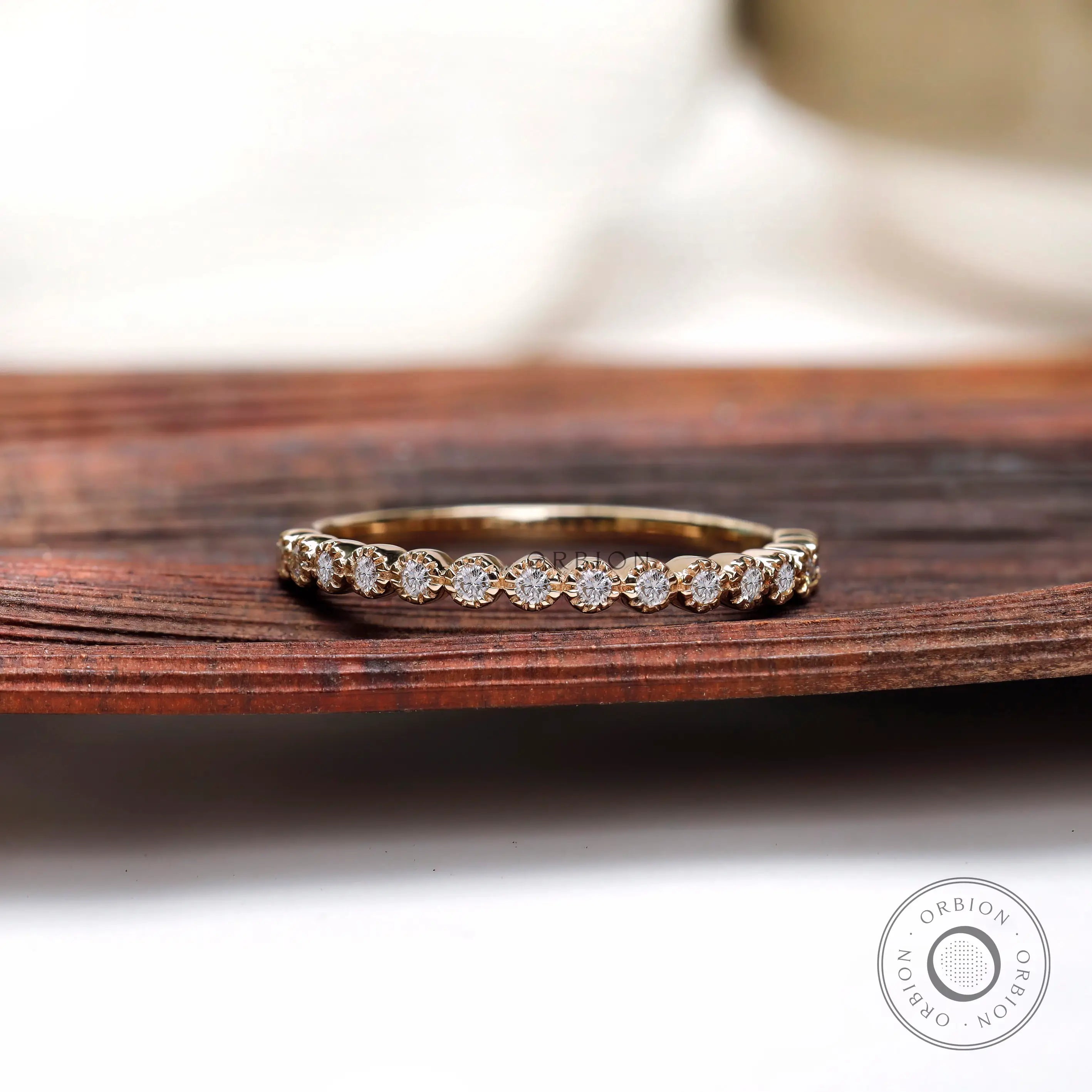 Half eternity bezel set moissanite band displayed on wooden surface front view