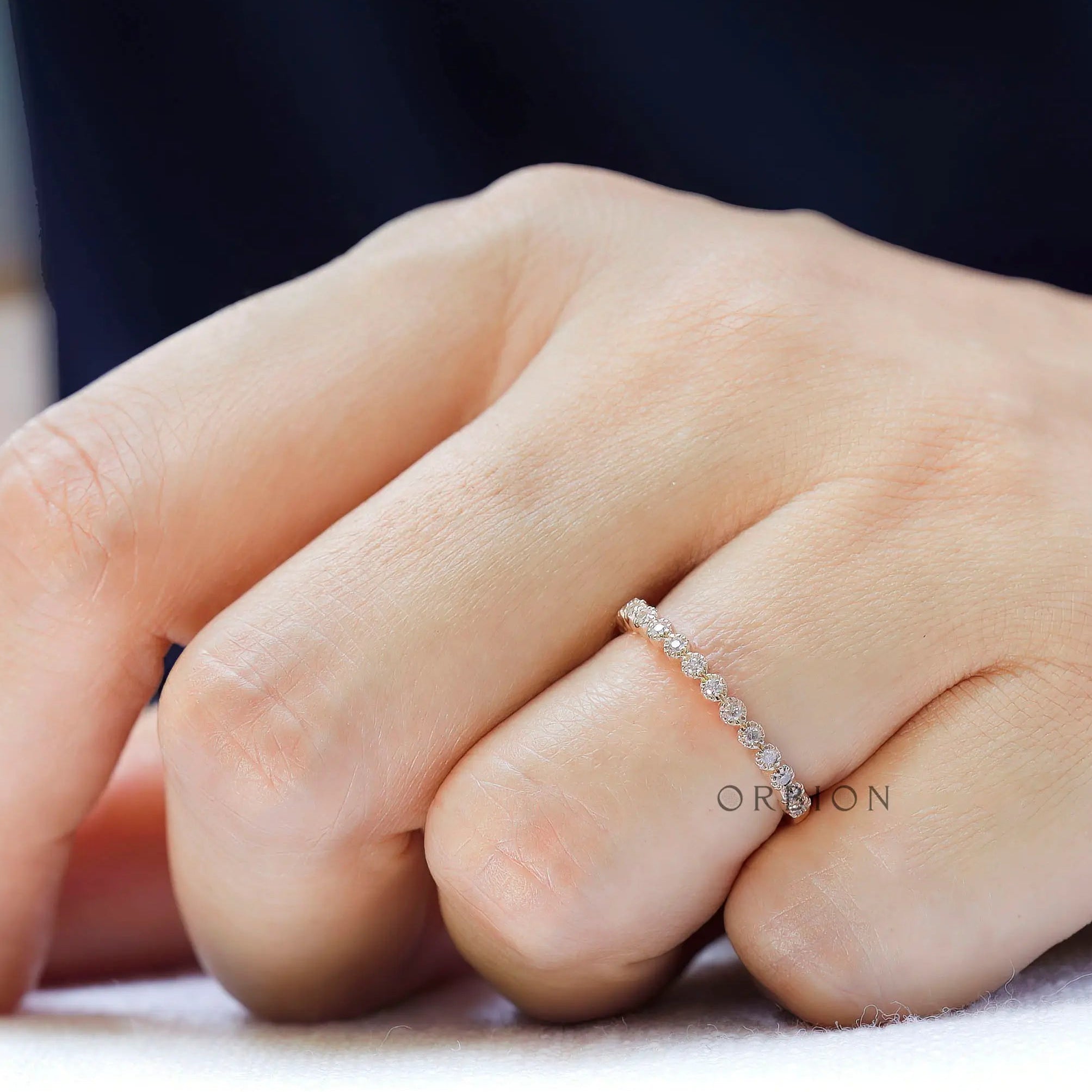 Art Deco bezel moissanite wedding band worn on finger close-up