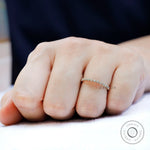 Dainty bezel set moissanite stacking band shown worn on hand