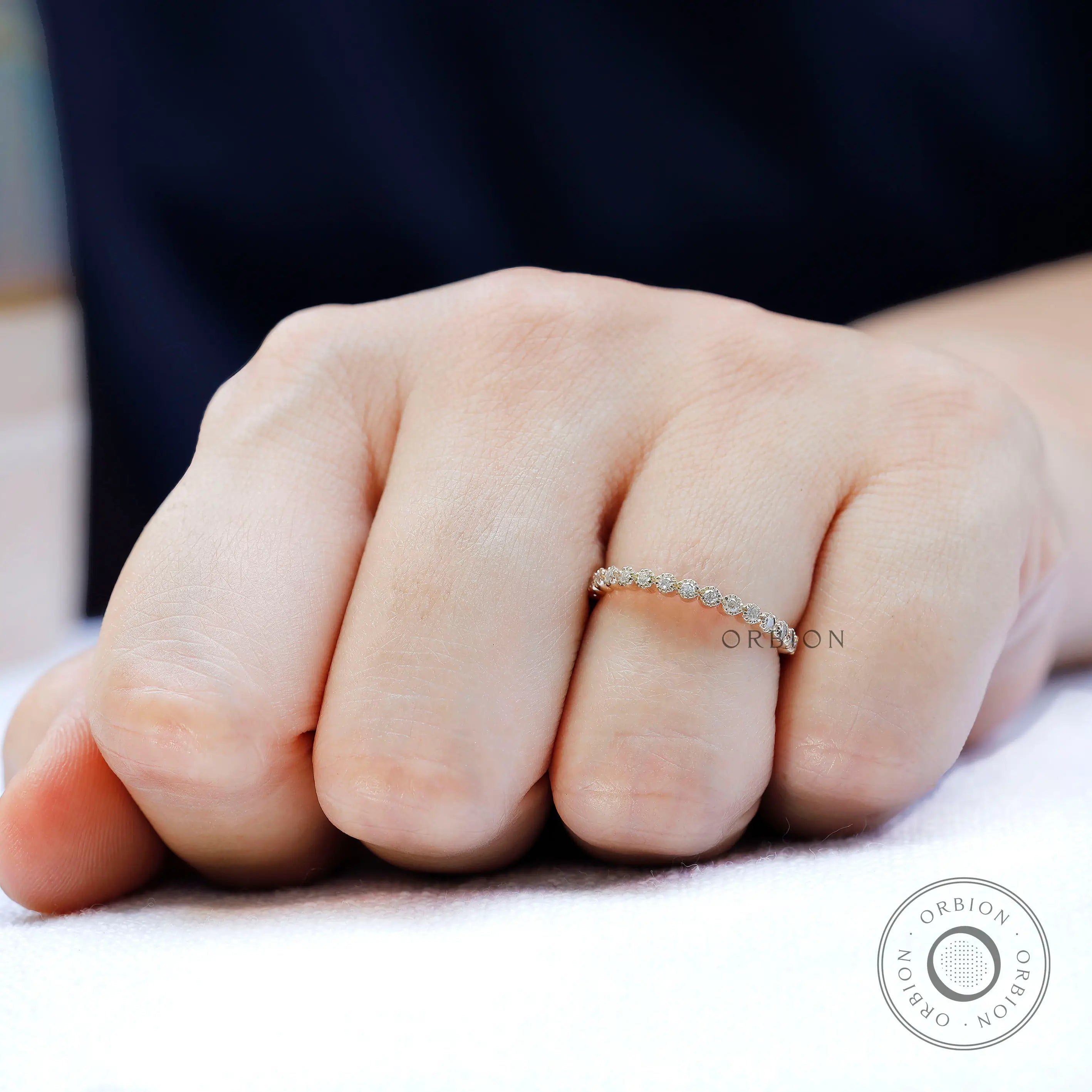 Dainty bezel set moissanite stacking band shown worn on hand