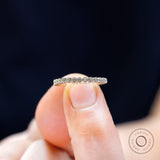 Close-up view of round moissanite stones in bezel setting on thin gold band