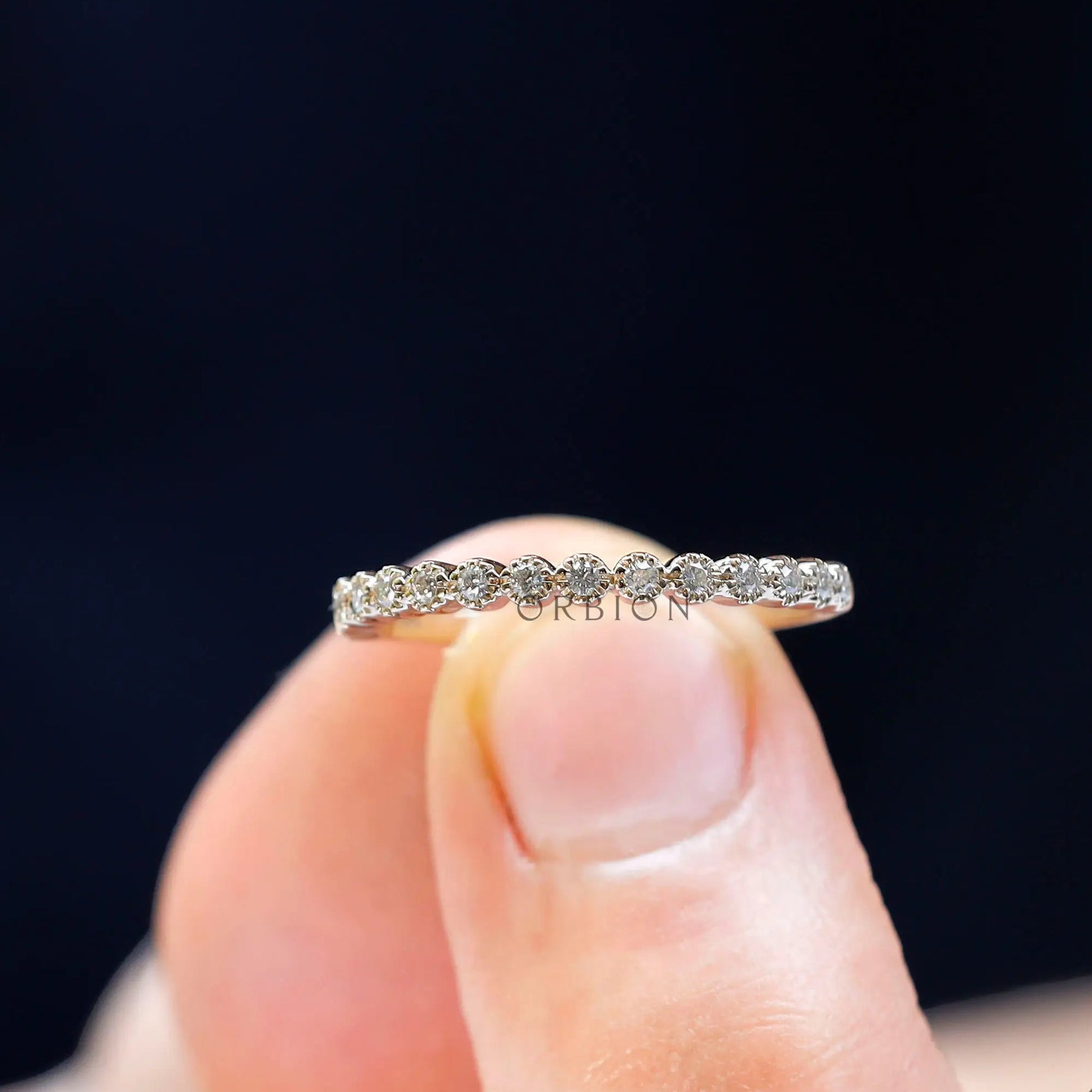 Close-up view of round moissanite stones in bezel setting on thin gold band