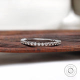 Bubble floating round cut moissanite eternity band displayed on wooden surface, front view