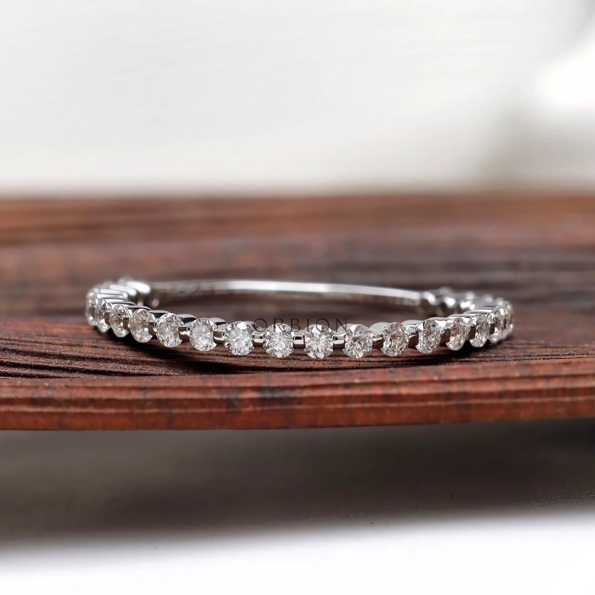 Bubble floating round cut moissanite eternity band displayed on wooden surface, front view