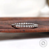 Shared prong round moissanite eternity wedding band angled side view on wood
