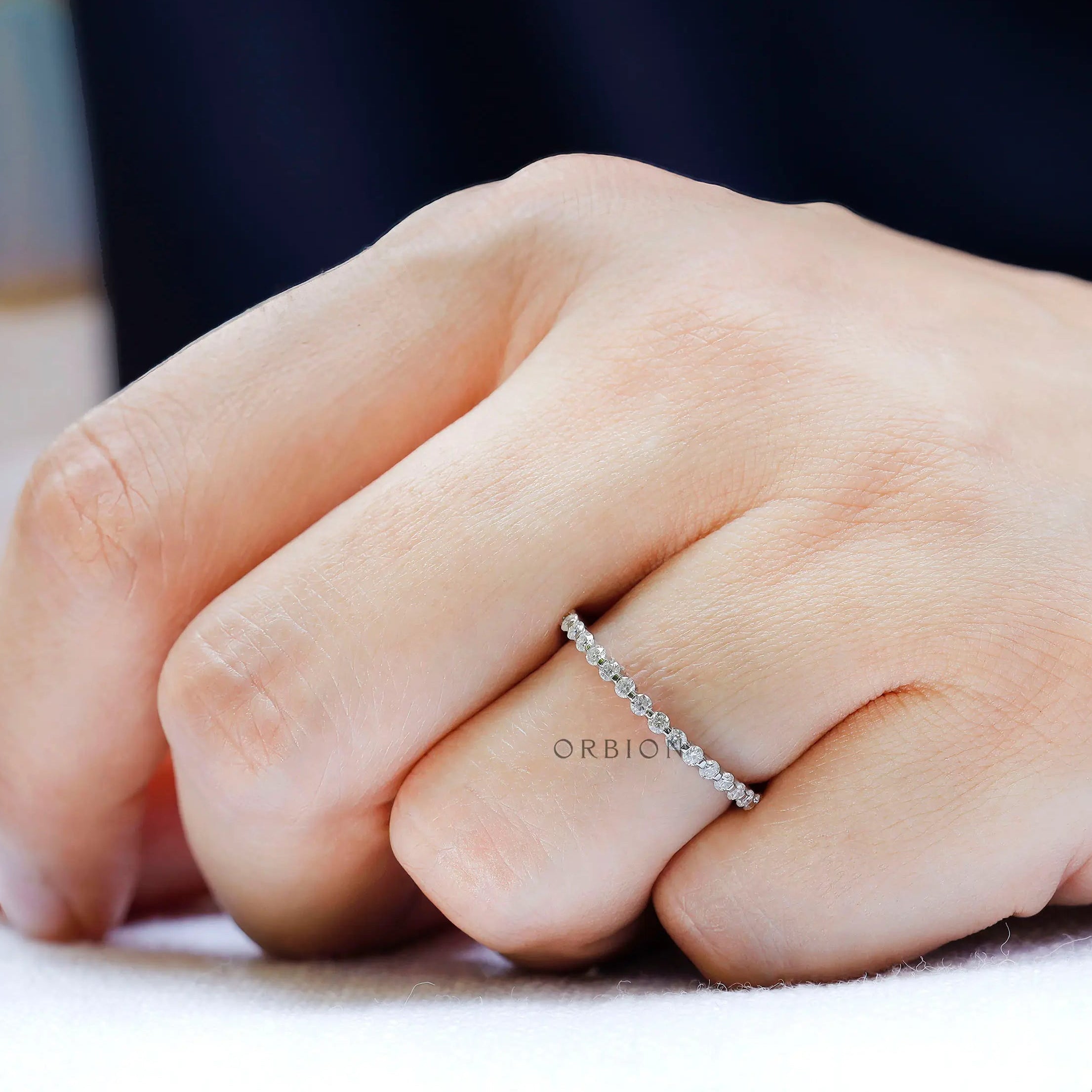 Slim shared prong moissanite eternity band worn solo on finger