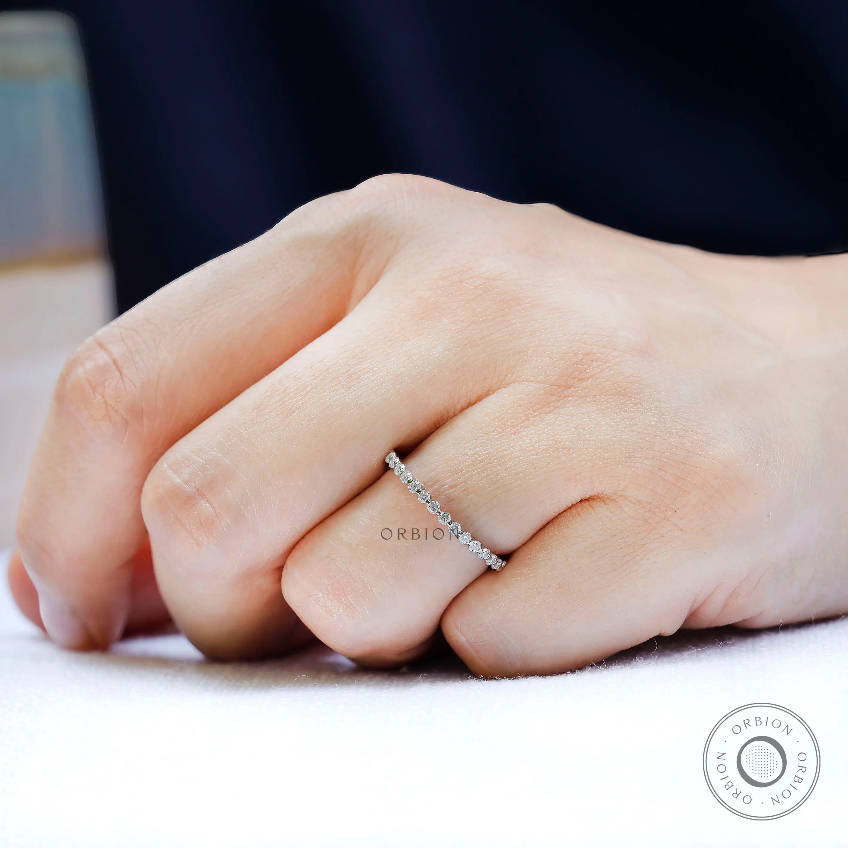 Slim shared prong moissanite eternity band worn solo on finger