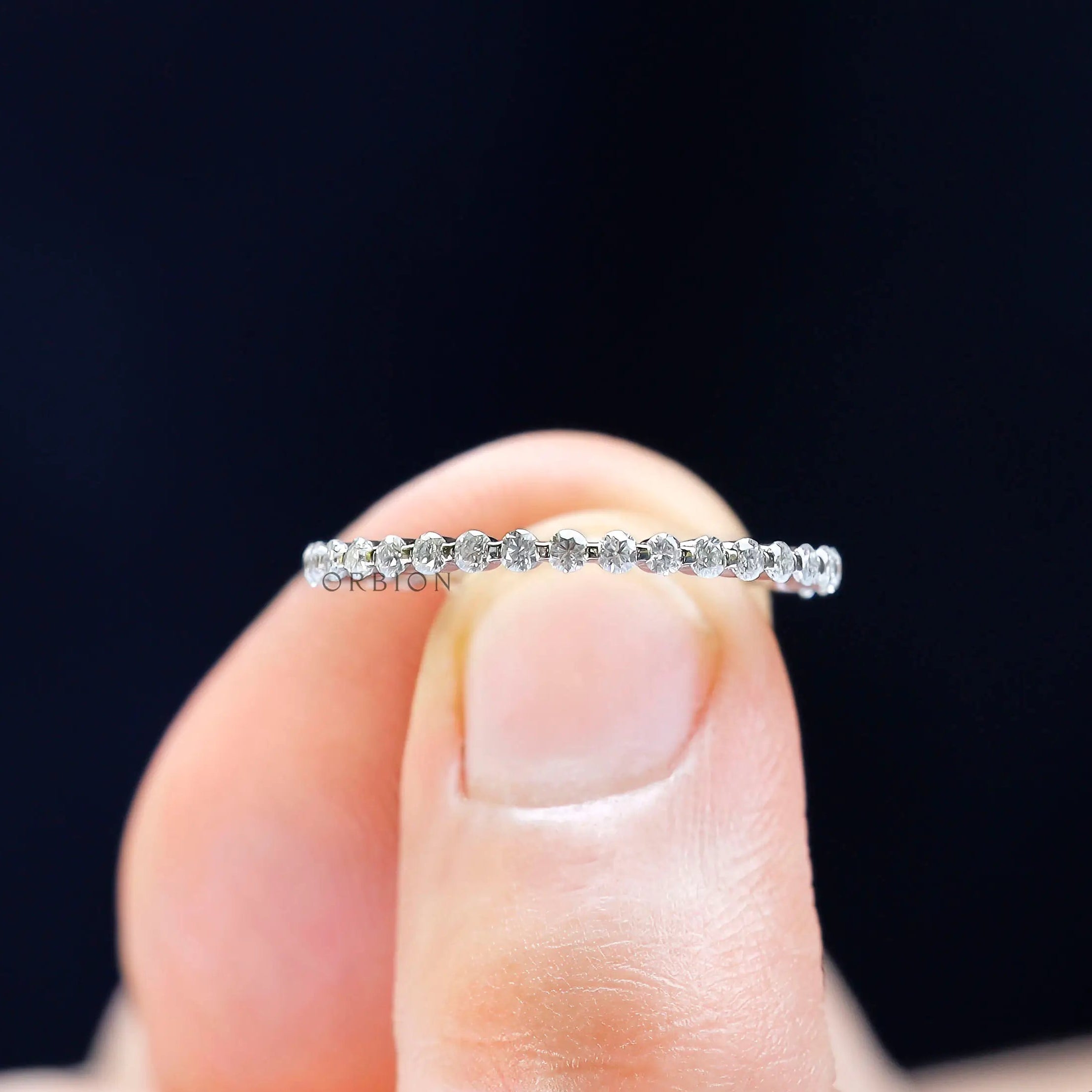 Close-up view of round cut moissanite stones in shared prong eternity band