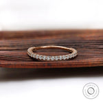 U-prong round eternity band in rose gold shown from front on wood backdrop