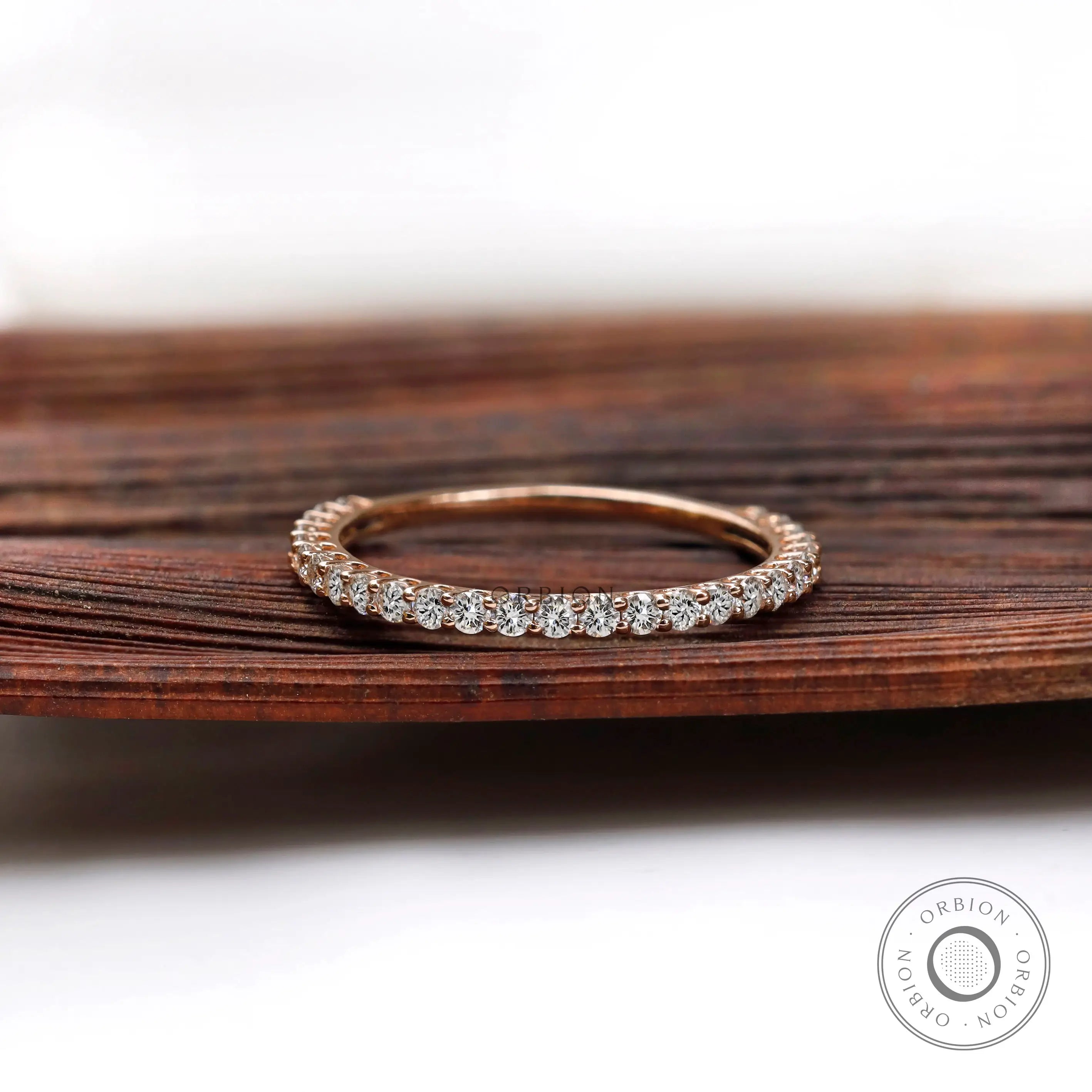 U-prong round eternity band in rose gold shown from front on wood backdrop