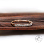 Side angle of slim U-prong eternity wedding band on wooden surface