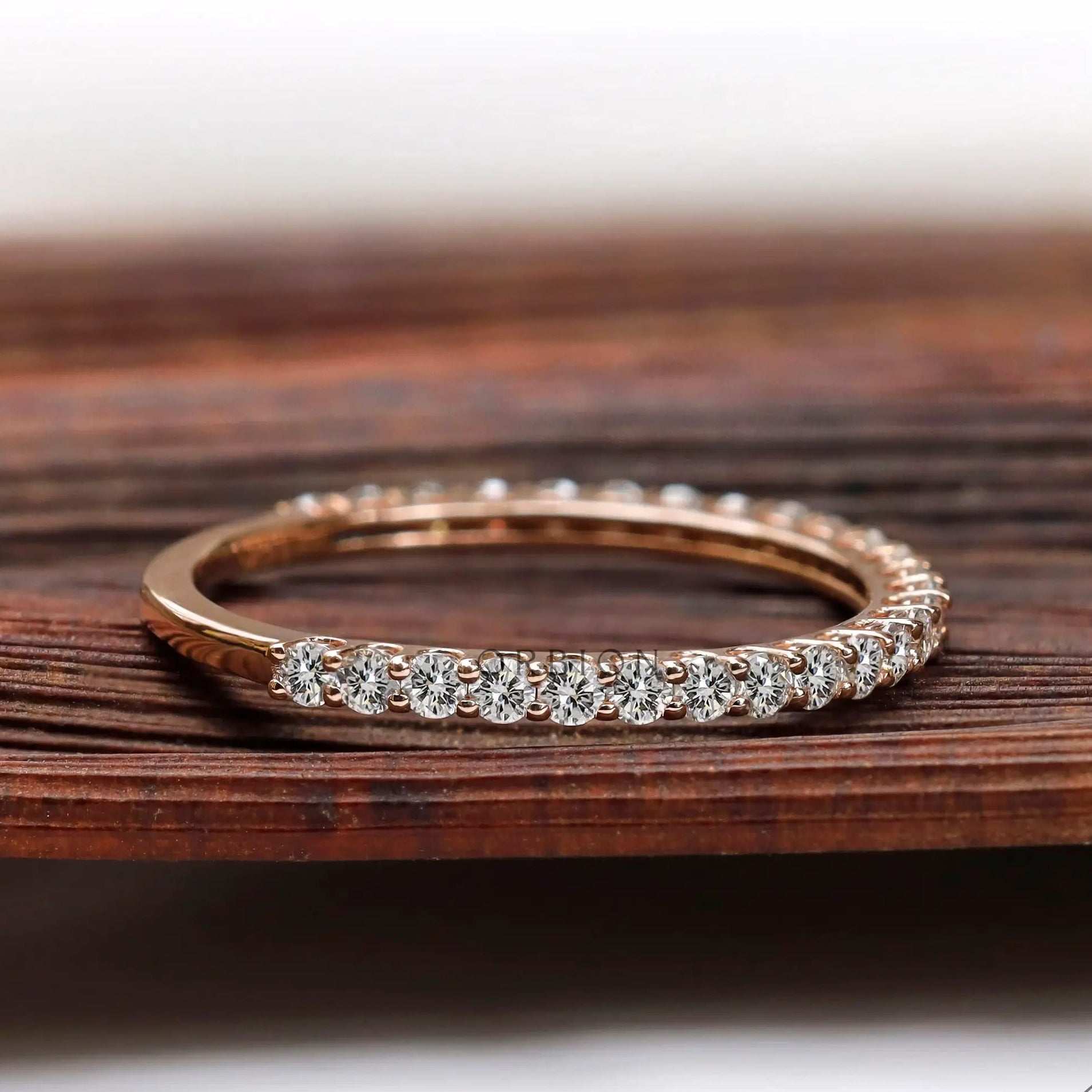 Side angle of slim U-prong eternity wedding band on wooden surface