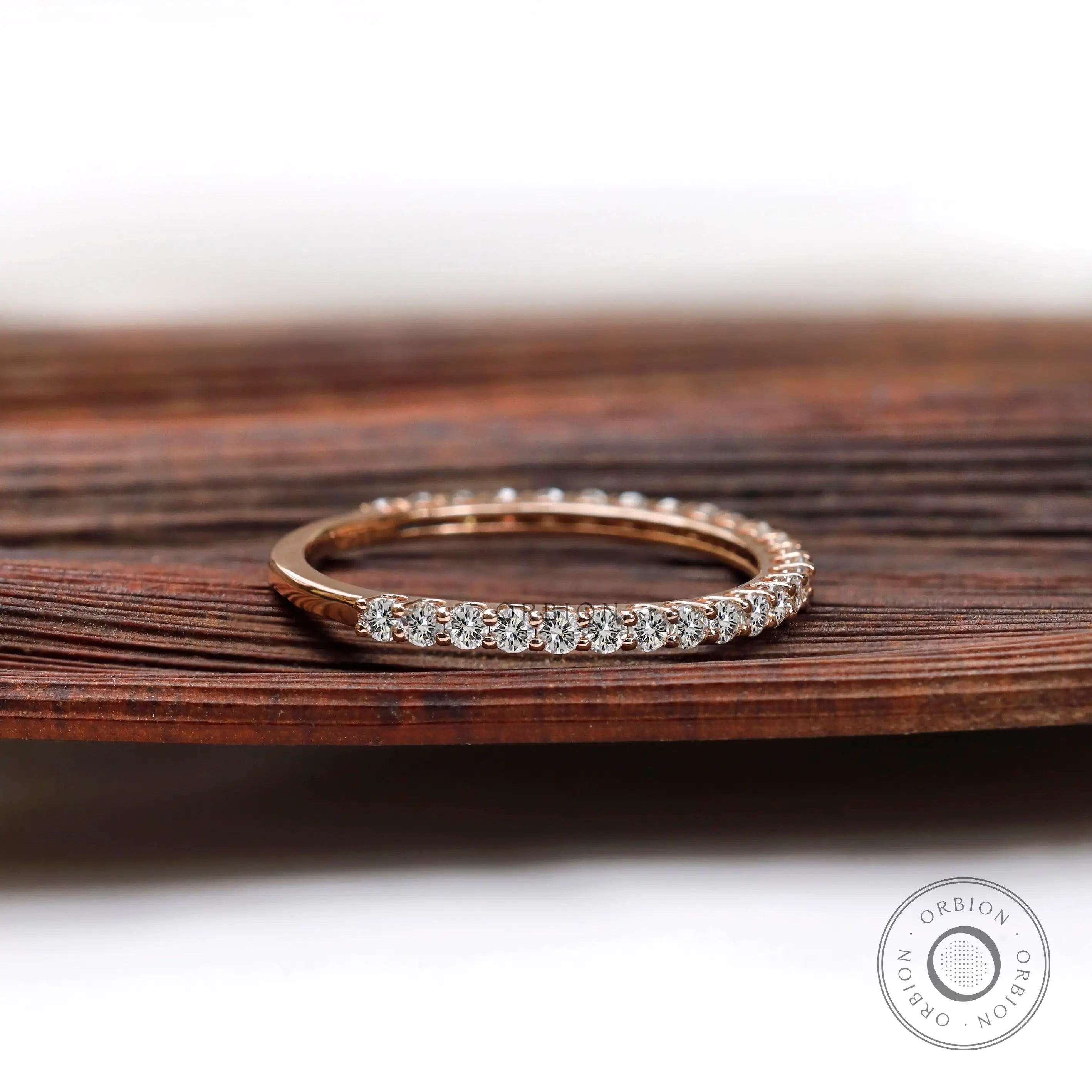 Side angle of slim U-prong eternity wedding band on wooden surface
