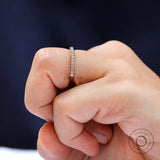 Close-up sparkle view of round moissanite eternity band worn on finger