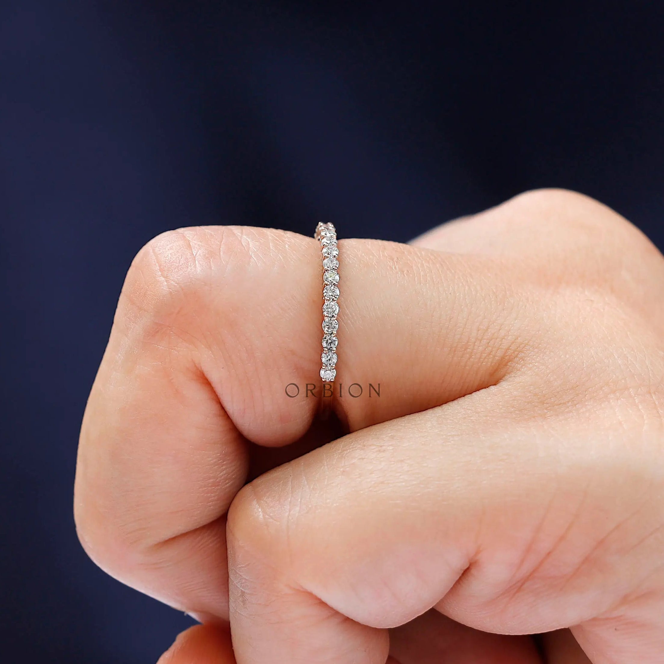 Close-up sparkle view of round moissanite eternity band worn on finger