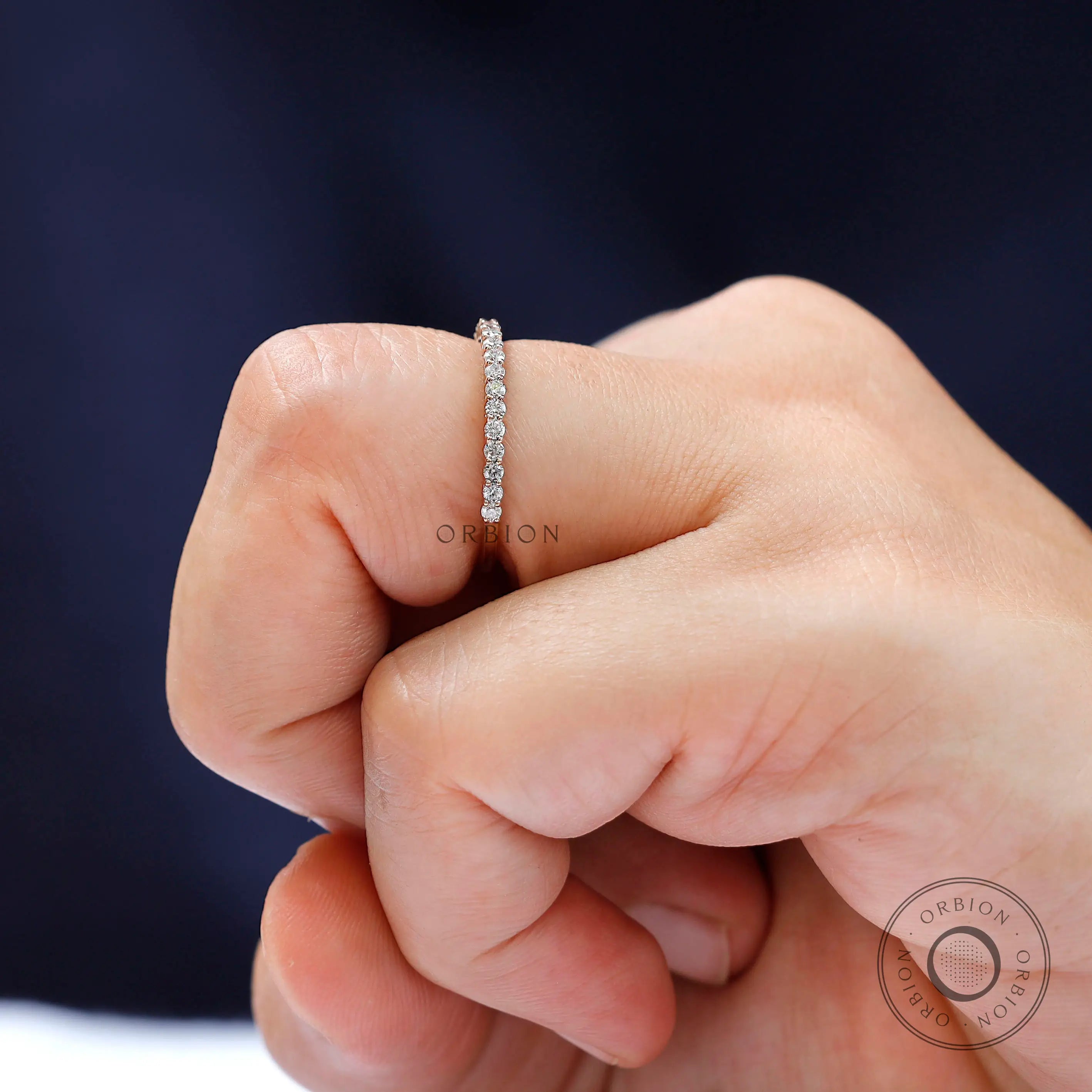 Close-up sparkle view of round moissanite eternity band worn on finger