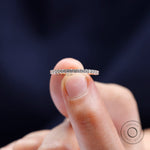 Close-up of U-prong round eternity band in rose gold held between fingers