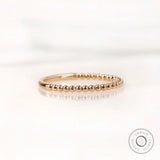 Angled side view of gold beaded wedding band highlighting slim profile