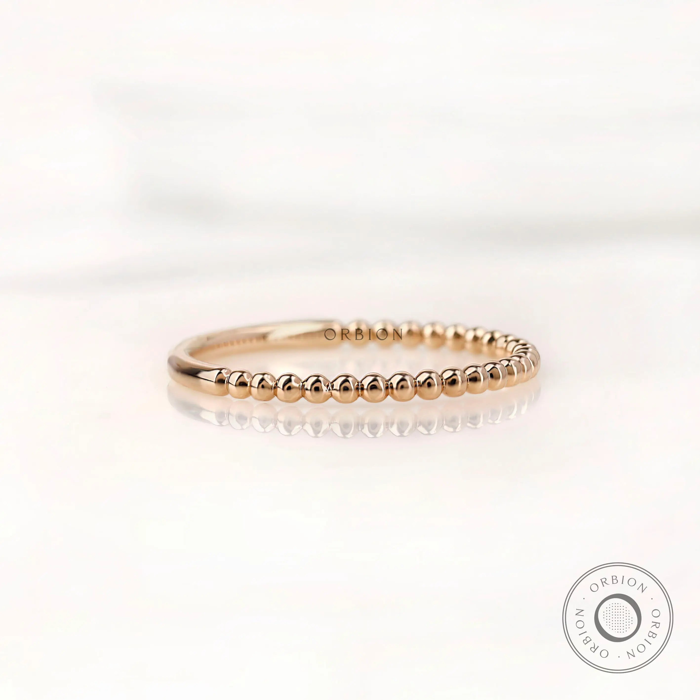 Angled side view of gold beaded wedding band highlighting slim profile