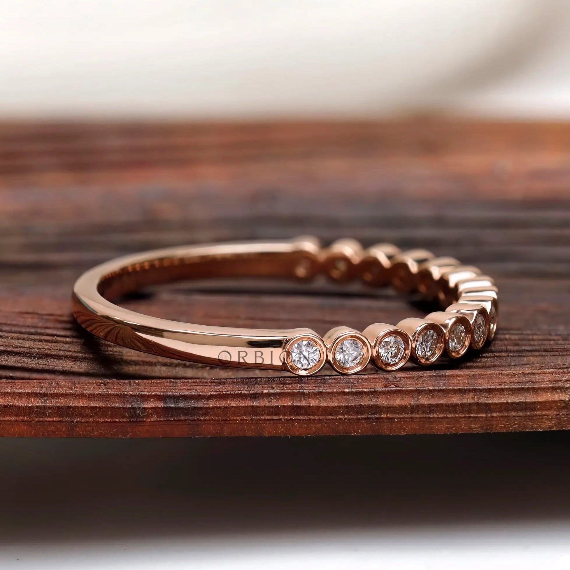 Side angle view of bezel set moissanite half eternity ring
