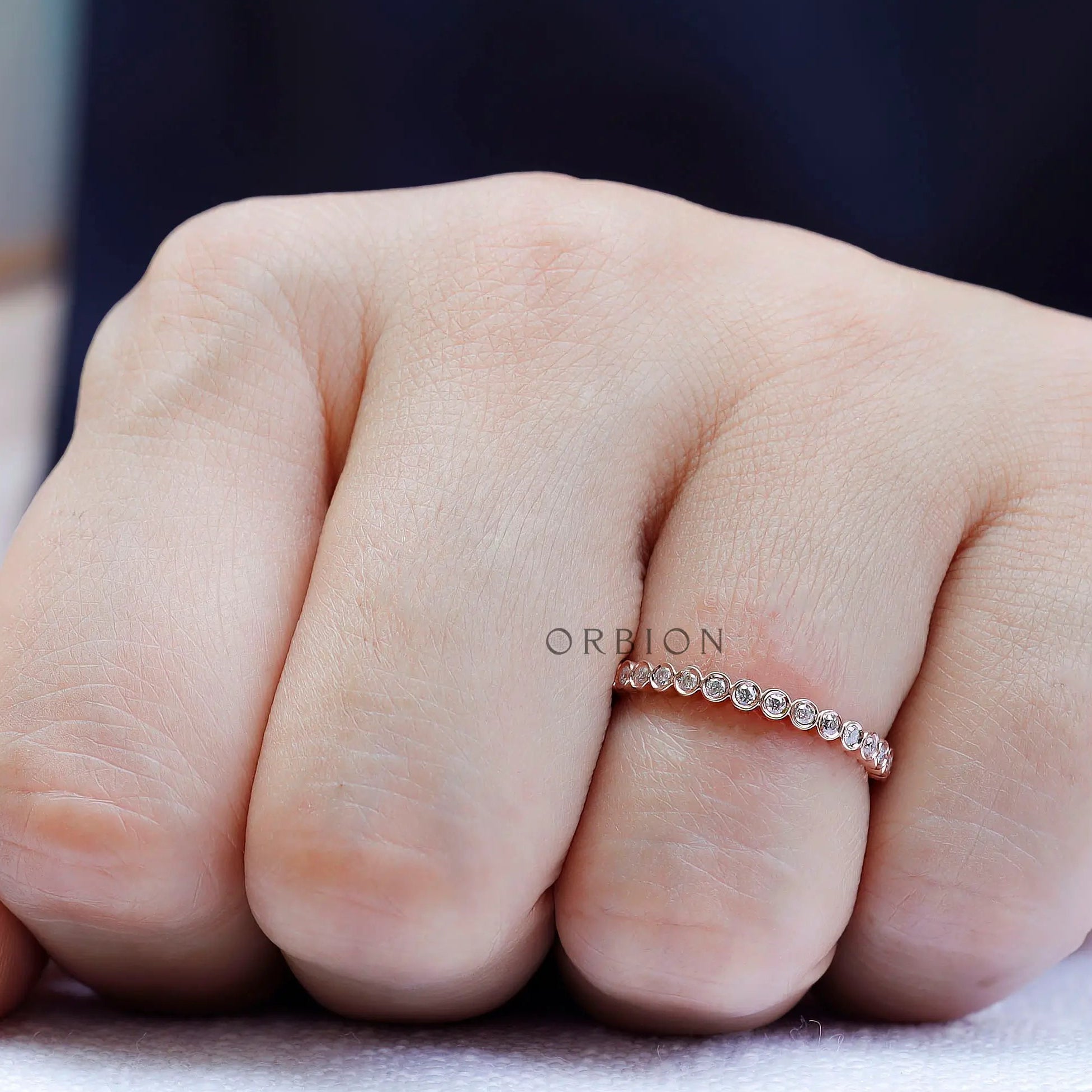 On-hand view of slim bezel set moissanite band worn