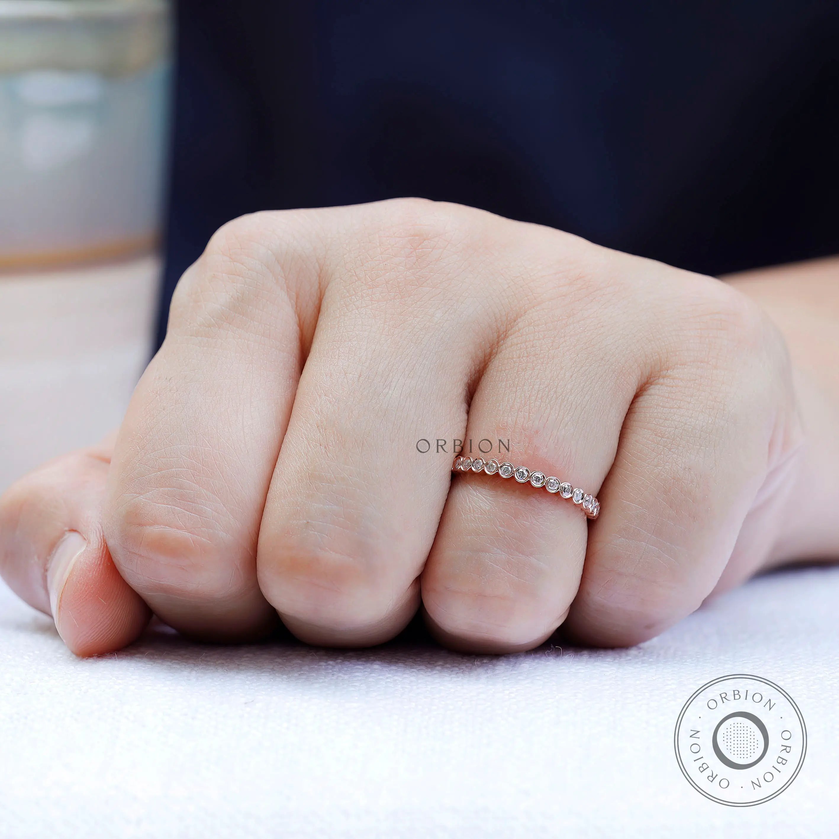 On-hand view of slim bezel set moissanite band worn