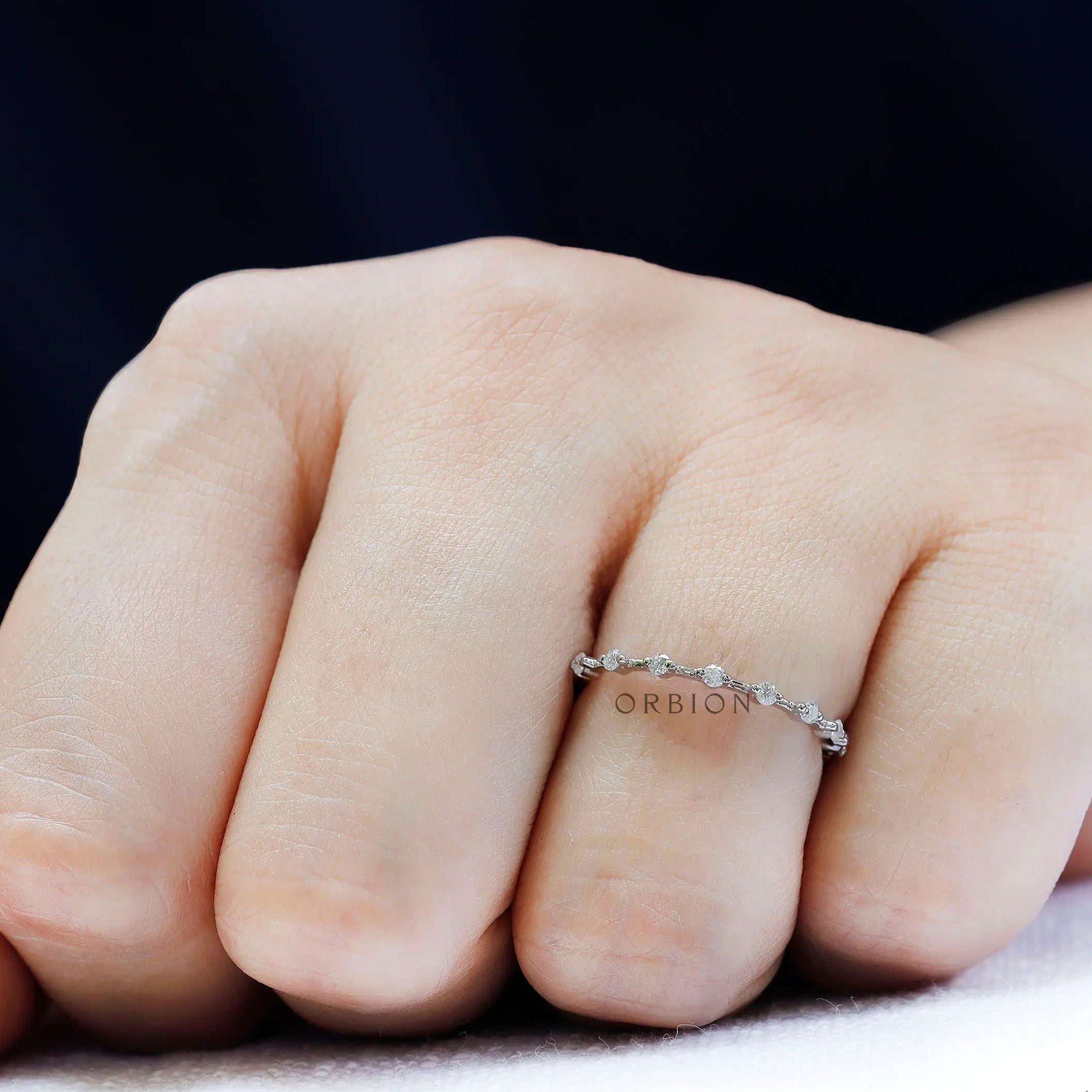 Dainty floating bubble moissanite band in white gold, angled on-hand view