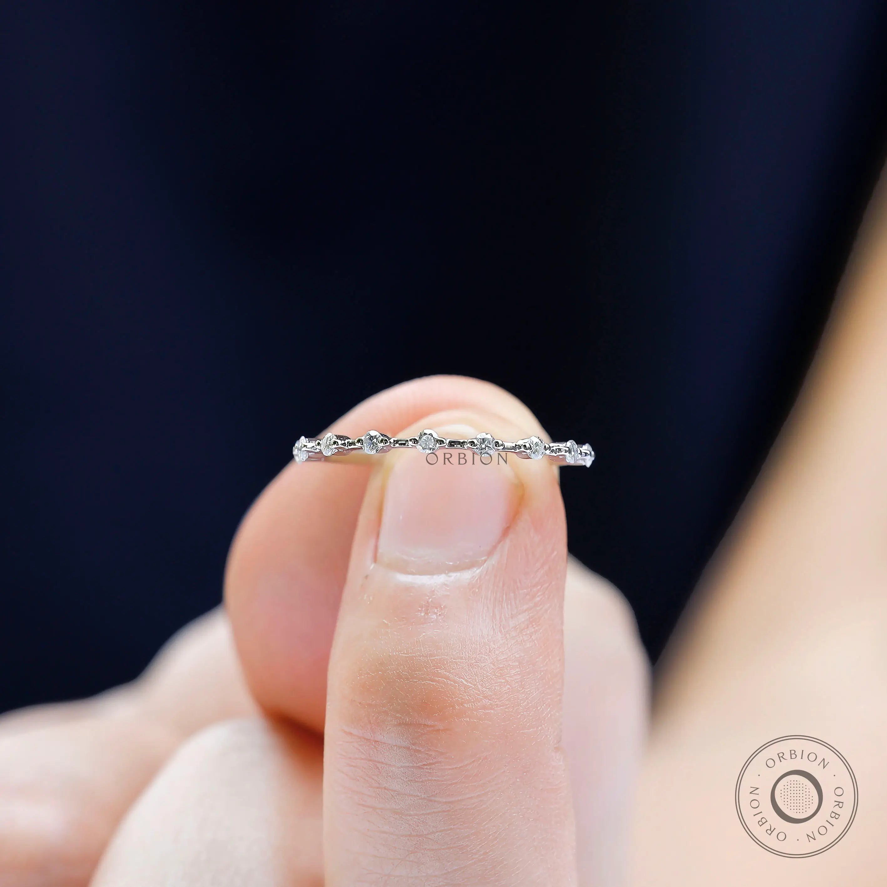 Worn fingertip view of delicate diamond beaded eternity band in white gold.