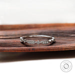 Dainty geometric moissanite wedding band displayed on wooden surface front view