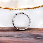 Top view of geometric bezel moissanite stacking band on white surface