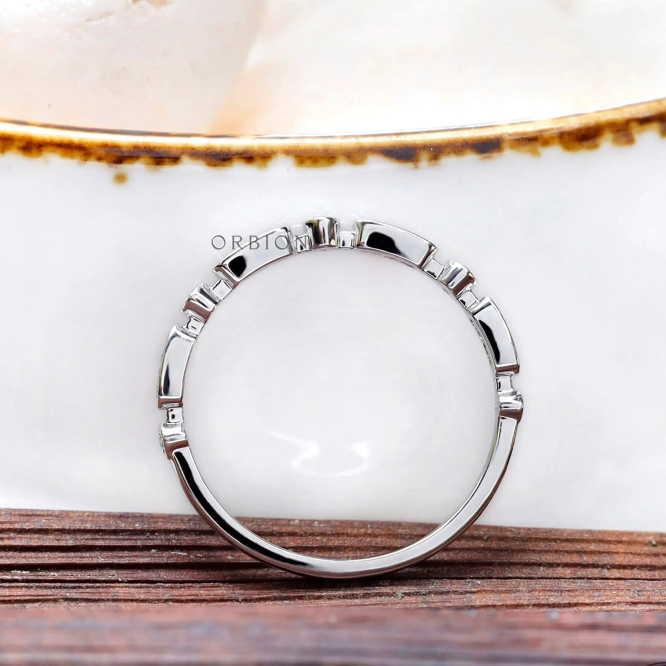 Top view of geometric bezel moissanite stacking band on white surface