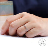 Dainty geometric moissanite wedding band worn on finger close-up