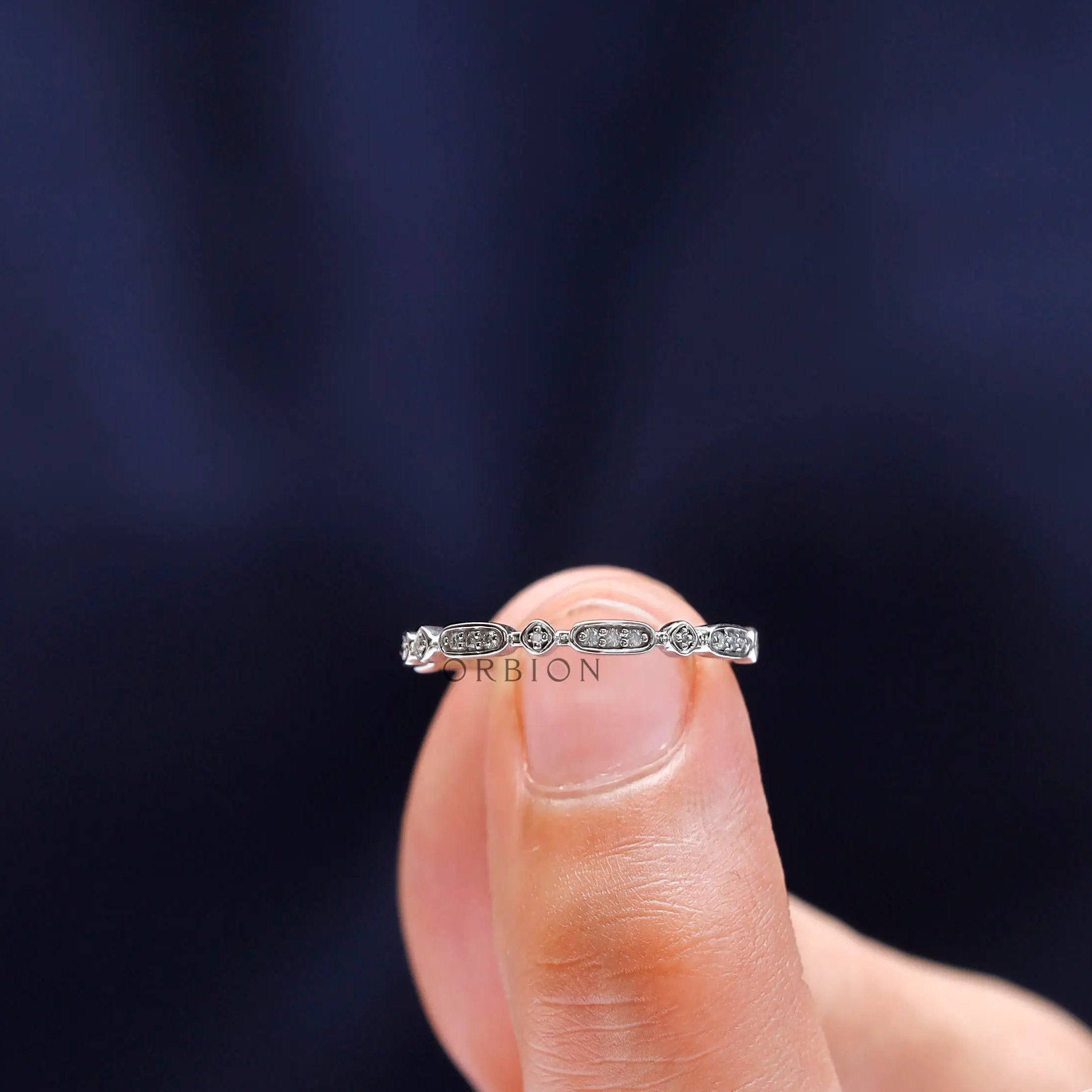 Close-up view of geometric moissanite stones arranged along slim gold band