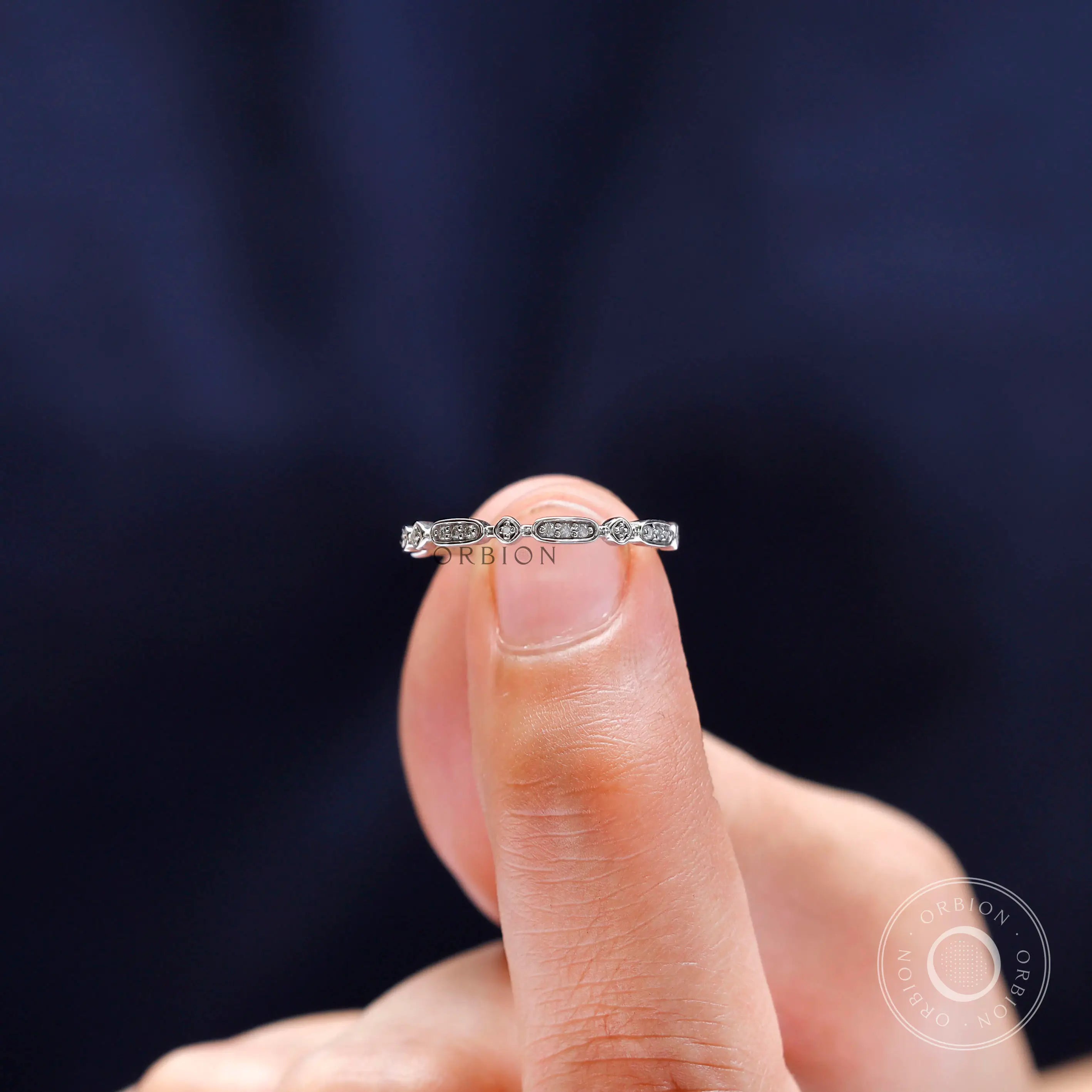 Close-up view of geometric moissanite stones arranged along slim gold band