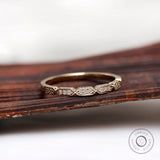 Geometric hexagon moissanite diamond wedding band resting on wooden surface