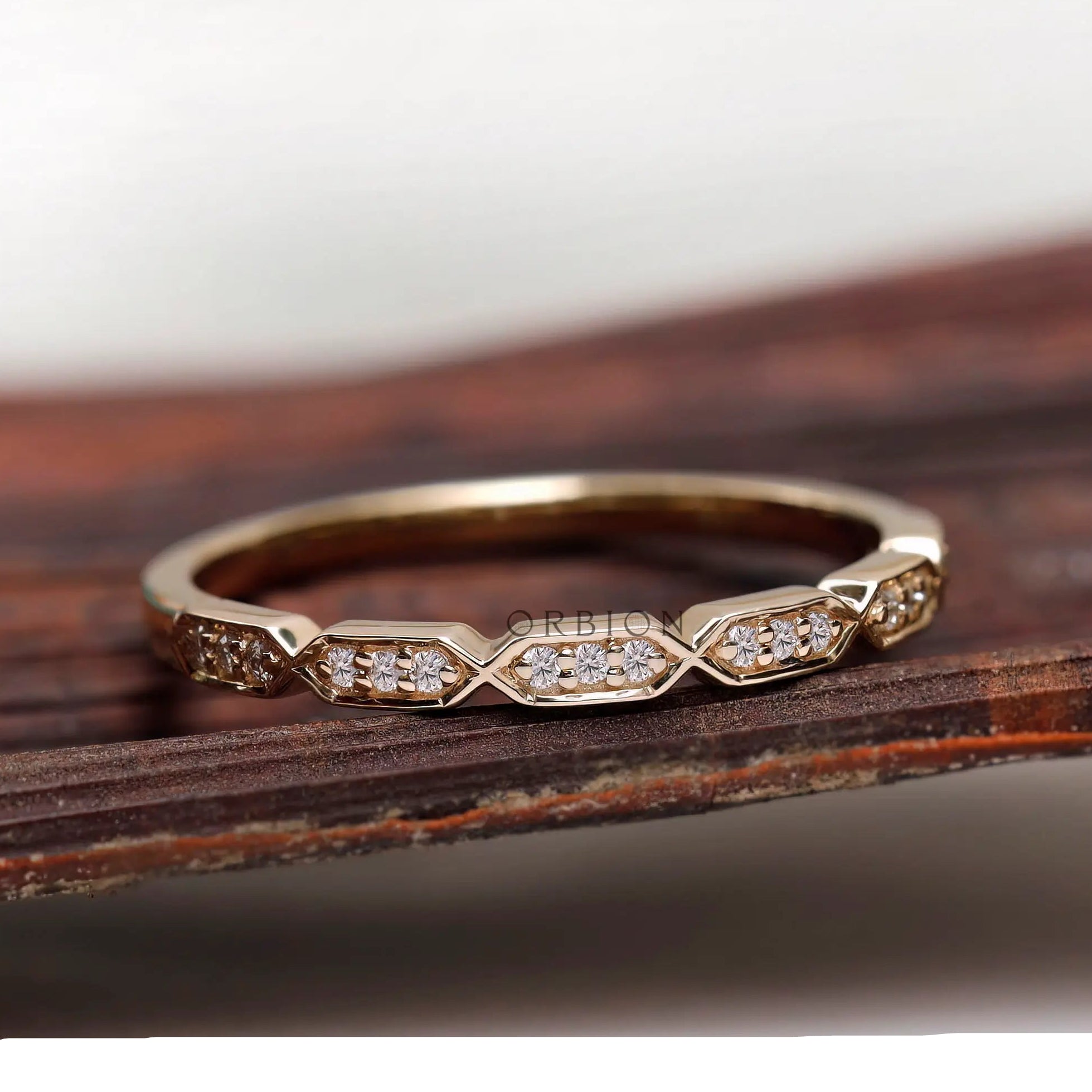 Geometric hexagon moissanite diamond wedding band resting on wooden surface