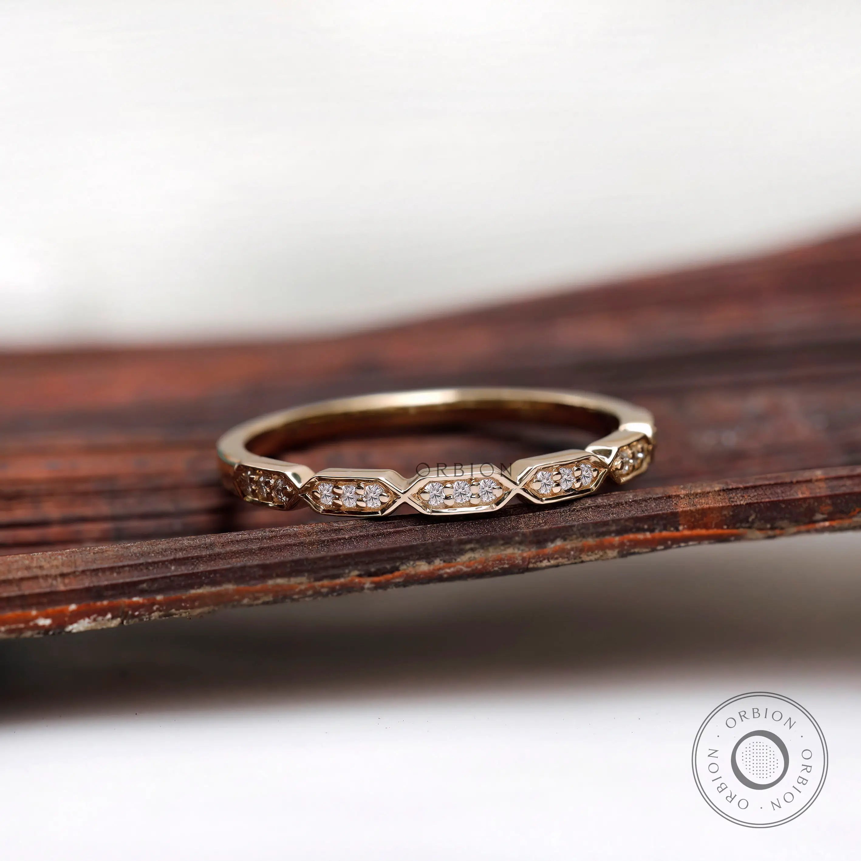 Geometric hexagon moissanite diamond wedding band resting on wooden surface