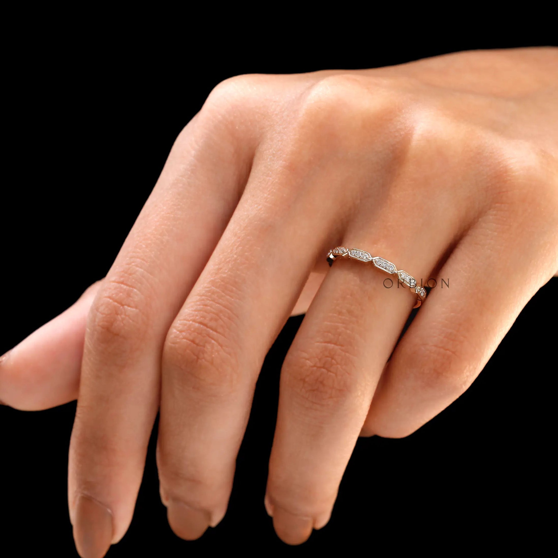 Geometric hexagon moissanite wedding band worn on finger close-up
