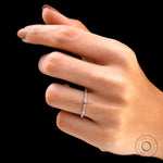 Hand wearing dainty geometric diamond stacking ring on black background