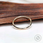 Thin plain yellow gold band on wooden surface