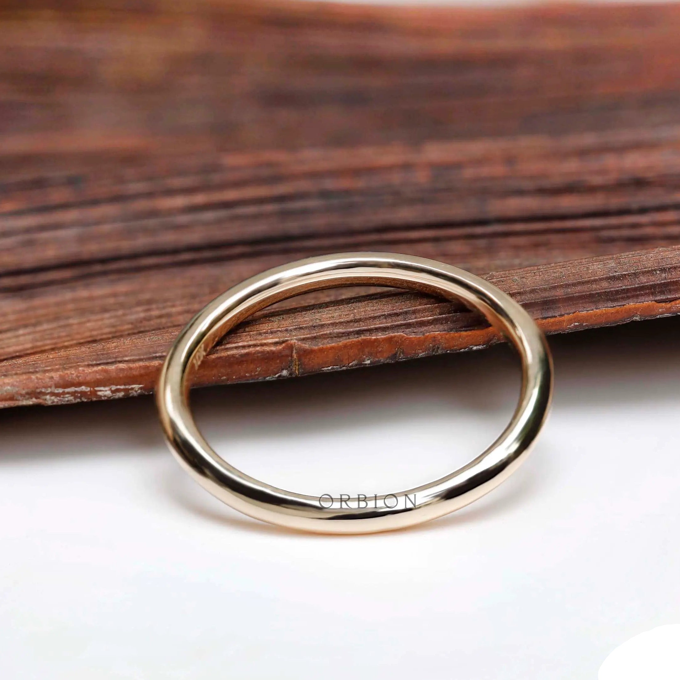 Thin plain yellow gold band on wooden surface