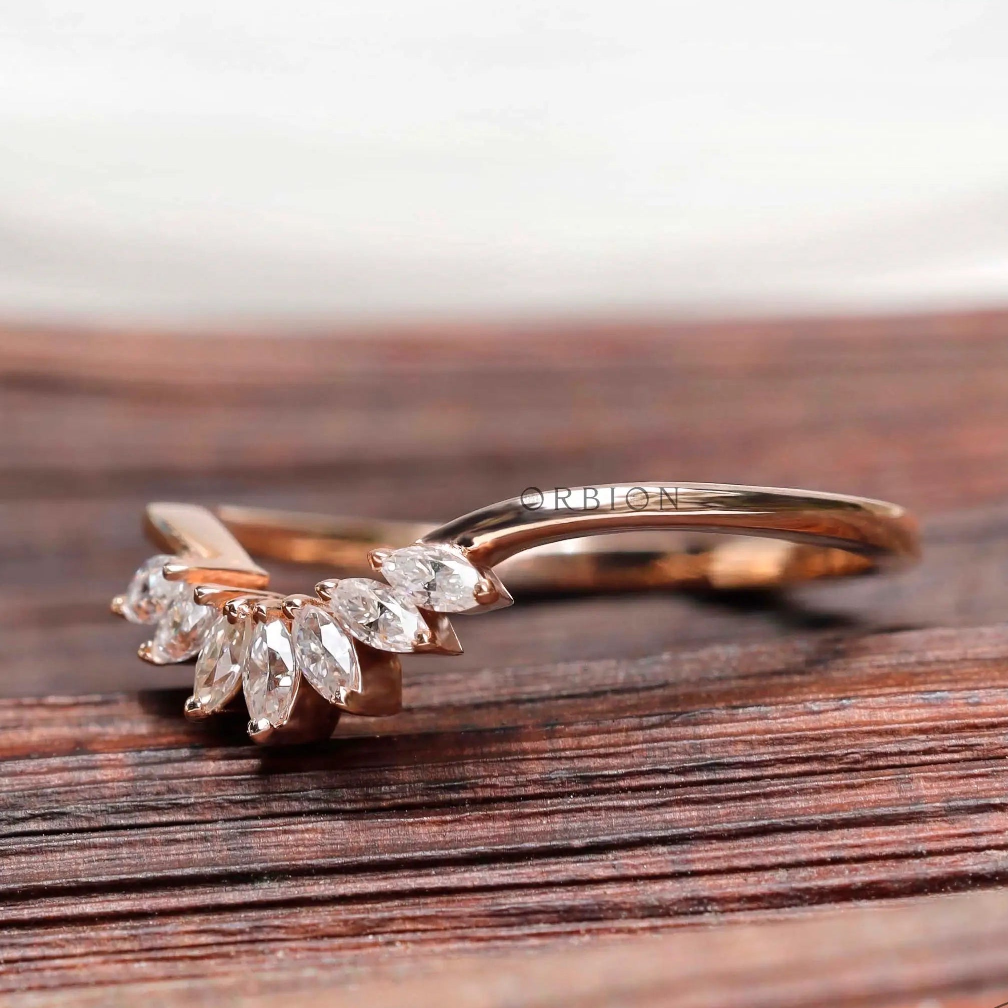 Angled view of marquise moissanite curved nesting band in rose gold