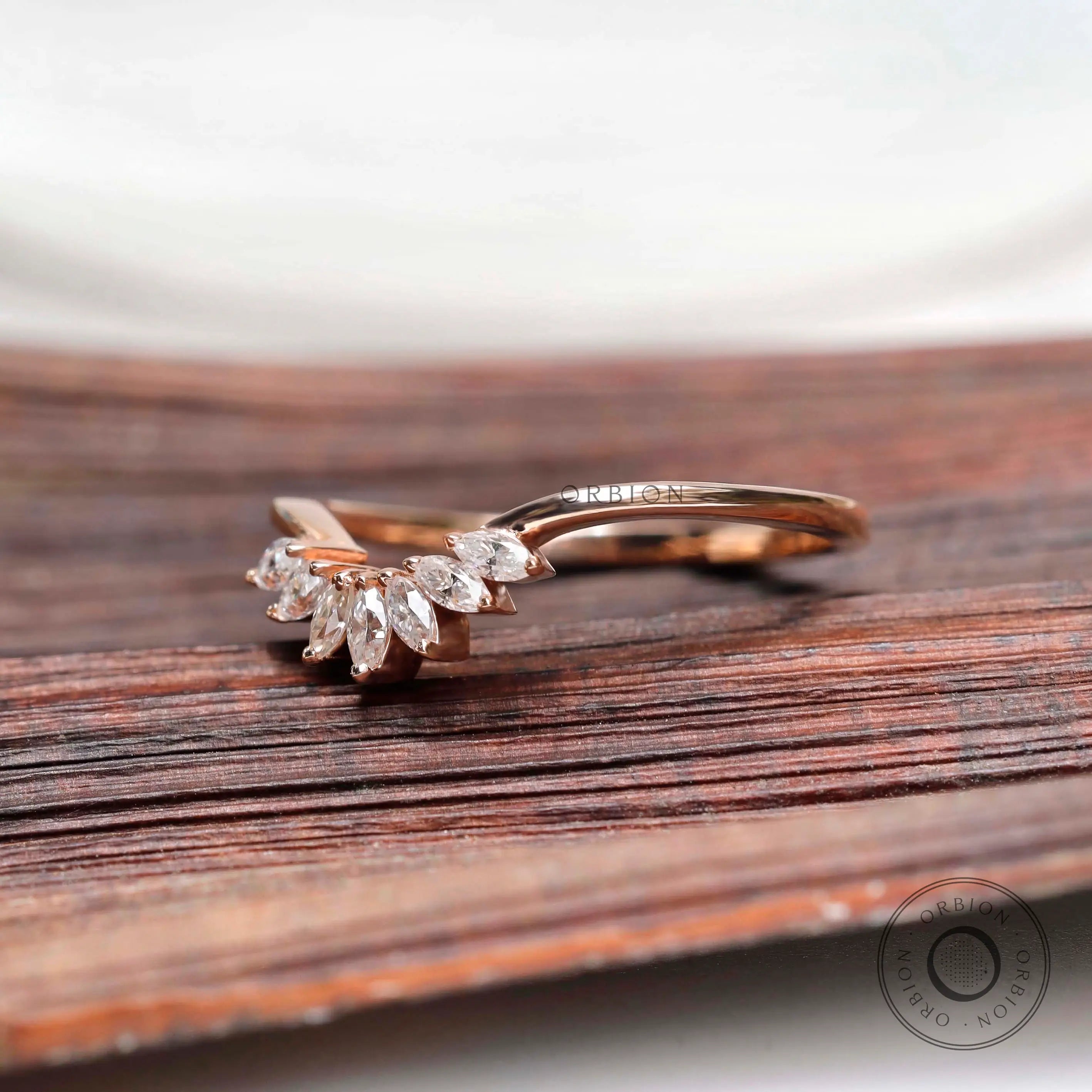 Angled view of marquise moissanite curved nesting band in rose gold