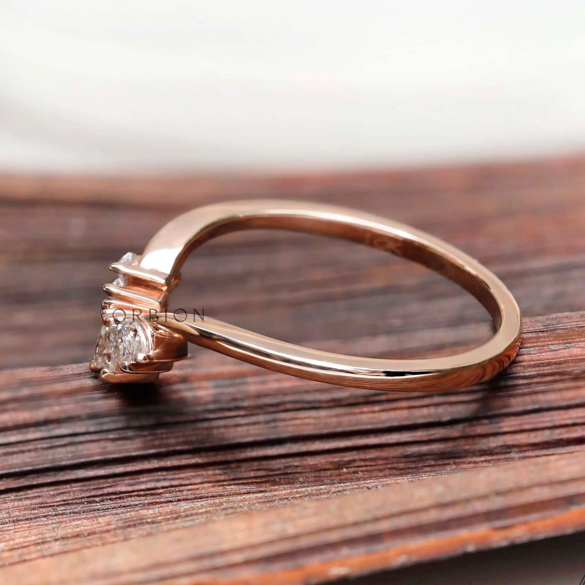 Side profile of curved marquise moissanite nesting band in rose gold