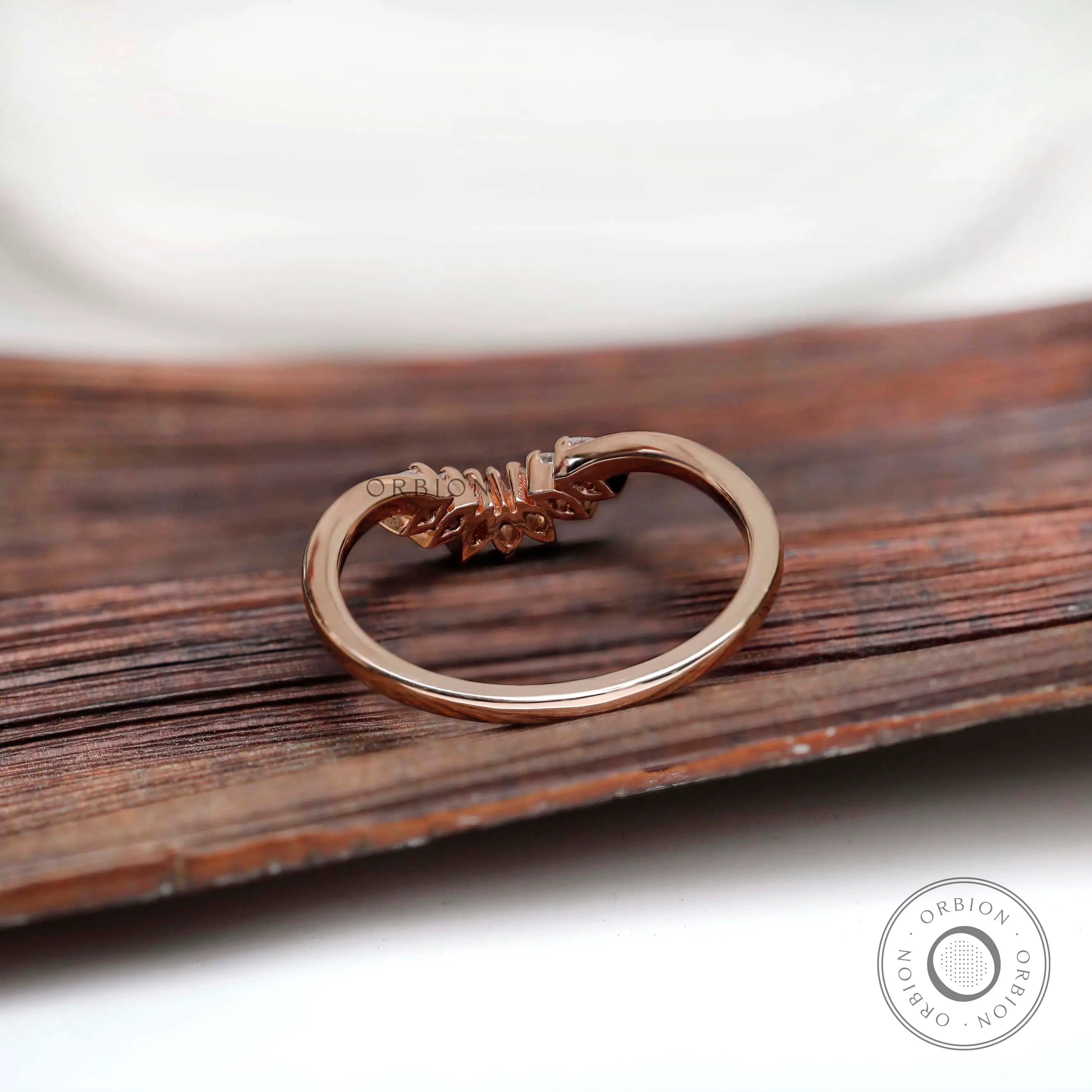 Back view of rose gold curved nesting band with marquise moissanite setting