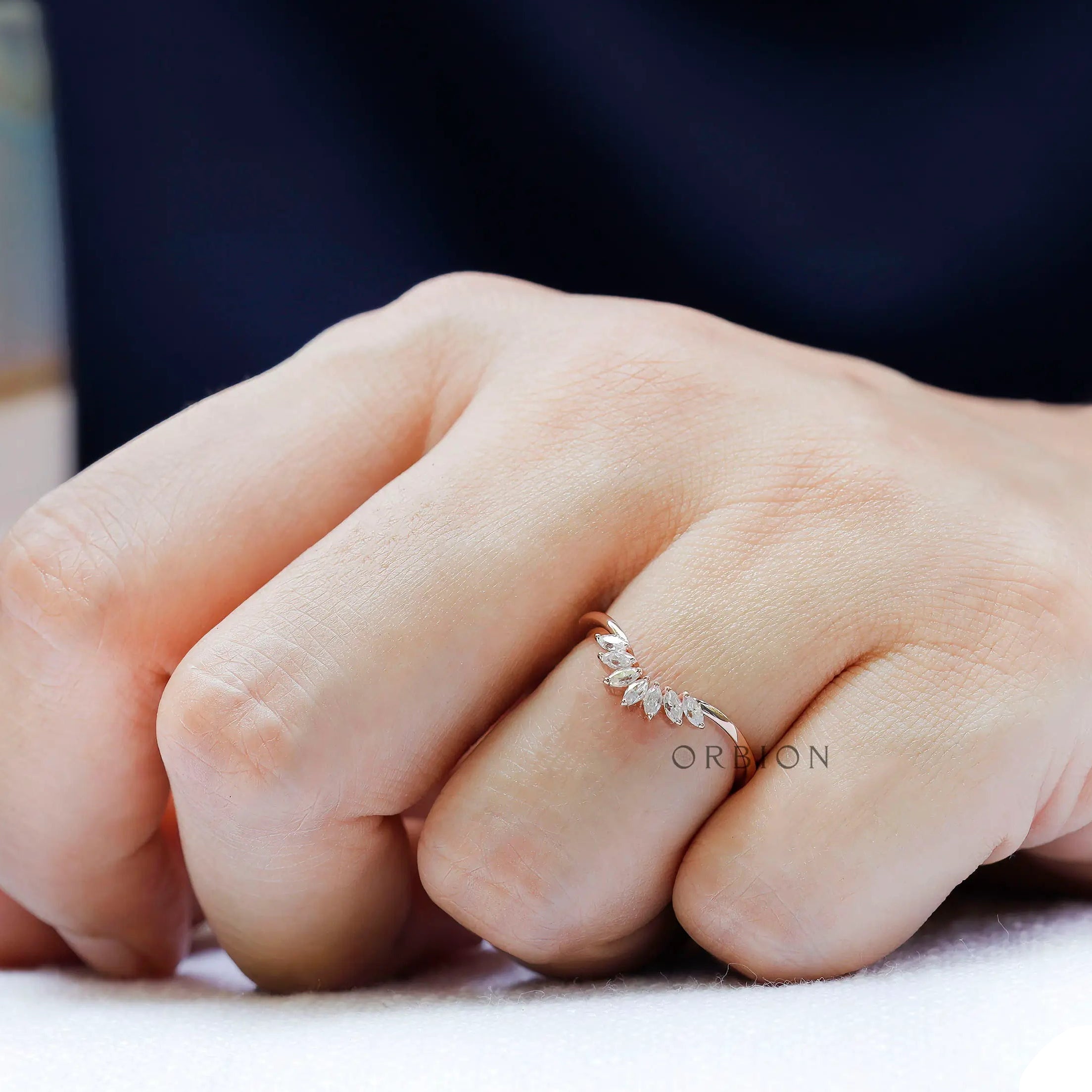 Curved marquise moissanite nesting band worn on hand in rose gold