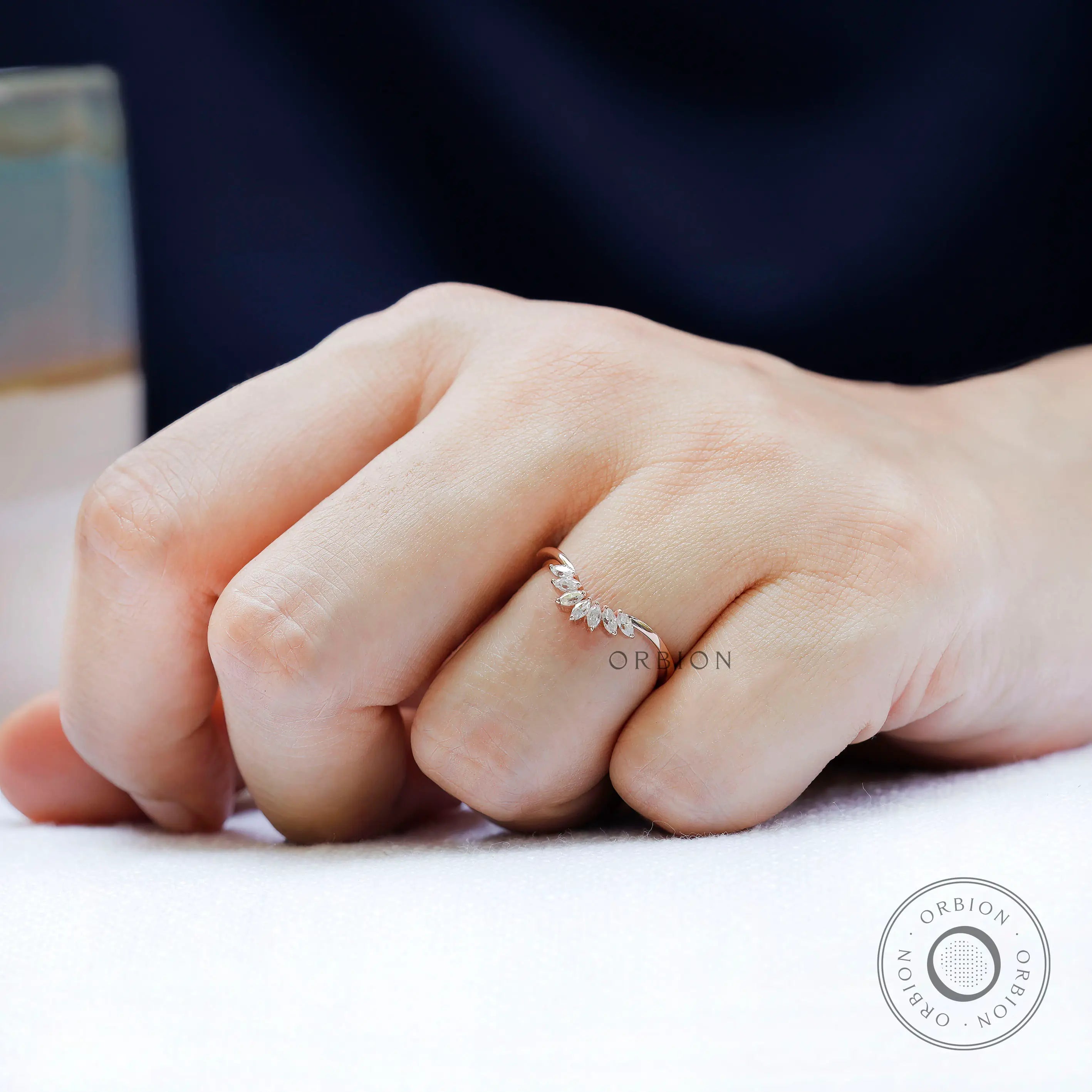 Curved marquise moissanite nesting band worn on hand in rose gold