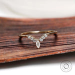 Front view of marquise and round cut chevron contour moissanite wedding band on wooden surface