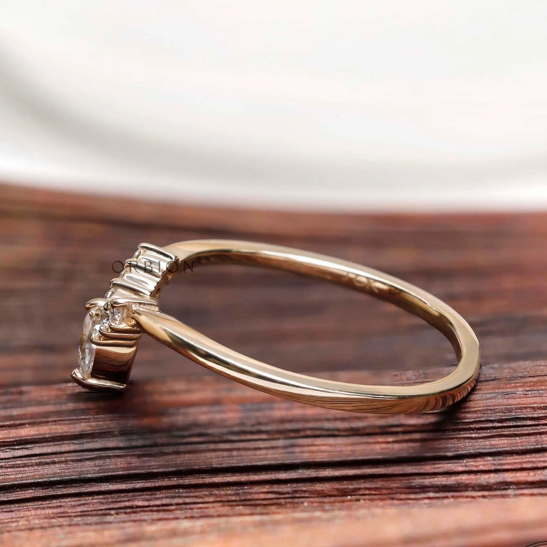 Side profile of marquise and round moissanite V shaped wedding band in solid gold